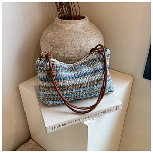 Close-up of a colorful wavy knit shoulder bag with brown leather knotted strap and ring detail