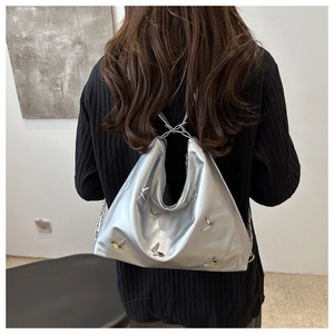 Detail of silver metallic hobo bag with 3D butterfly accents and chain strap