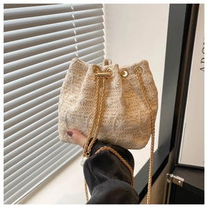 Detail of cream woven bucket bag with floral embroidery and gold chain drawstring