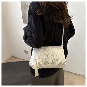 Close-up of beige New Chinese style crossbody bag with embroidery and tassel on model