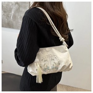 Detail of floral embroidery and white tassel on cream white Chinese style shoulder bag