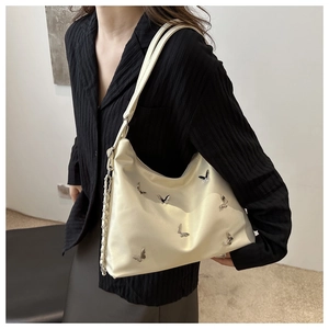 Detail of cream leather hobo bag with silver butterfly studs on a model shoulder
