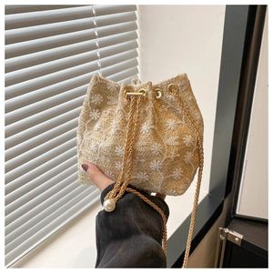 Close-up of woven straw bucket bag with white floral embroidery and pearl chain detail