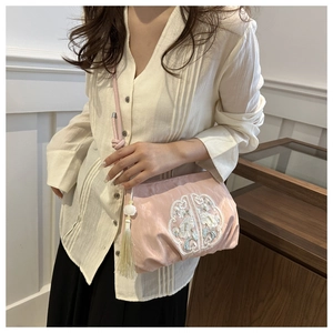 Détail du sac en satin rose avec broderie florale blanche et pendentif à pompon