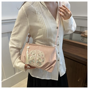 Close-up of pink crossbody bag with traditional embroidery and silk tassel detail