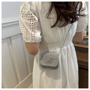 Detail of silver butterfly clasp and pleated texture on light blue crossbody saddle bag