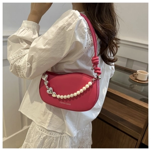 Sac à bandoulière fuchsia avec breloques perles et cœur porté par un mannequin