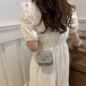 Silver butterfly crossbody saddle bag with chain strap shown on a model for styling