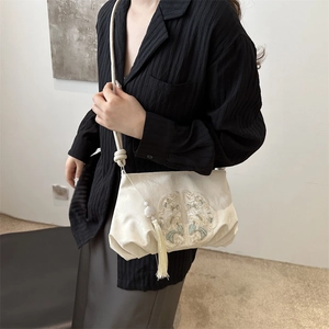 Off-white embroidered crossbody bag with floral pattern and tassel on model