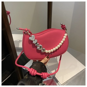 Détail du sac bandoulière rose fuchsia avec chaîne décorative cœurs argentés et perles