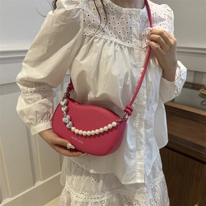 Sac bandoulière fuchsia avec chaîne de perles et cœurs sur tenue en dentelle blanche