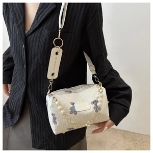 Détail du sac blanc à relief avec motif d'ours et chaîne décorative en perles