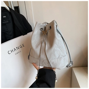 Detail of silver bucket bag with butterfly metal drawstring lock and pearl pendants