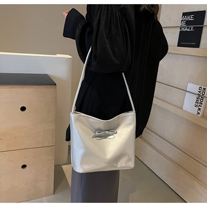 Detail of silver metallic bucket bag with stylish bow accent and modern leather texture