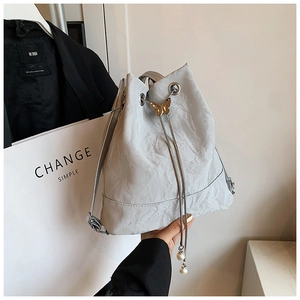 Detail of grey pleated leather bucket bag with gold butterfly and pearl tassel accent