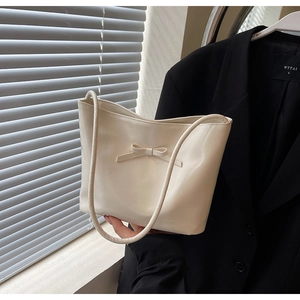 Close-up of a cream-colored PU leather hobo bag featuring an elegant bow detail and dual straps