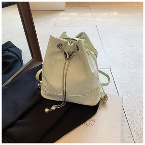 Detail view of light green bucket bag with butterfly metal buckle and pearl charms