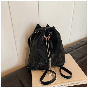 Detail of black pleated bucket bag with butterfly metal buckle and pearl pendant charm