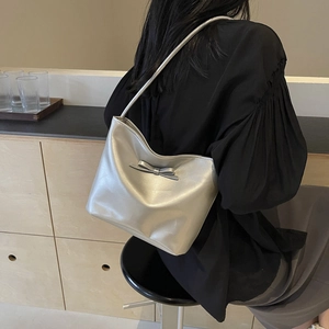 Chic silver metallic bucket bag with bow detail shown on shoulder in a stylish setting
