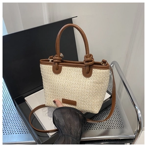 Detail der handgewebten Stroh-Eimertasche mit hochwertigen braunen Ledergriffen und Trägern