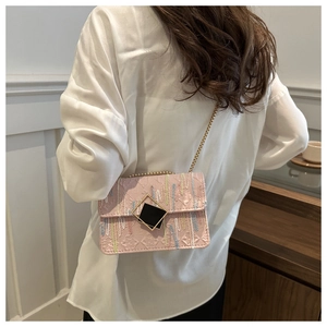 Close-up of pink shoulder bag featuring geometric embossing and colorful embroidery