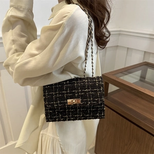 Elegant black tweed chain shoulder bag with gold hardware and flap closure on model