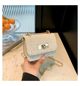 Detail view of woven straw crossbody bag with golden metal twist lock and chain strap
