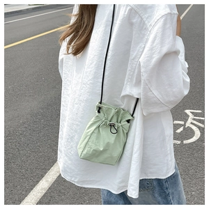 Detail of mint green nylon drawstring crossbody bag with adjustable black shoulder strap
