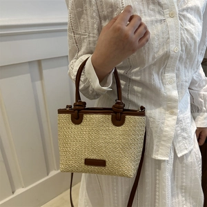 Handgewebte Stroh-Eimertasche mit dunkelbraunem Lederbesatz und Umhängegurt für den Sommer