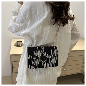 Detail of a chic black square chain bag with colorful wave embroidery and gold metal clasp