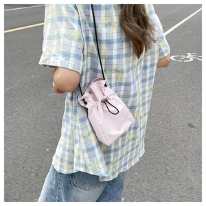 Pink drawstring bucket bag in lightweight canvas shown in a casual outdoor setting
