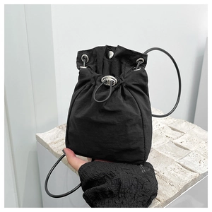 Detail of minimalist black nylon drawstring bucket bag with silver metal buckle and strap