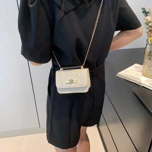 Straw woven crossbody bag with gold chain and metal lock shown on model's shoulder