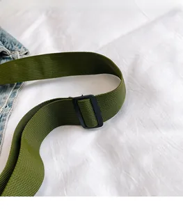 Detail view of adjustable army green canvas bag strap with black buckle on white fabric