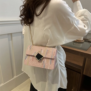 Pink shoulder bag with colorful wave embroidery and gold chain strap on white shirt