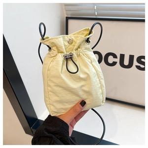 Detail of cream nylon bucket bag featuring metallic snap closure and adjustable black drawstring