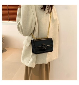 Side view of a black leather shoulder bag with a gold metal buckle and chain strap