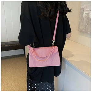 Detail of pink twill crossbody bag with knot handle and gold hardware on model