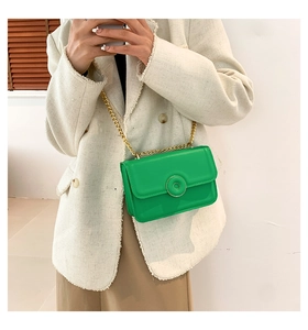 Detail view of bright green leather crossbody bag with elegant gold chain and round buckle