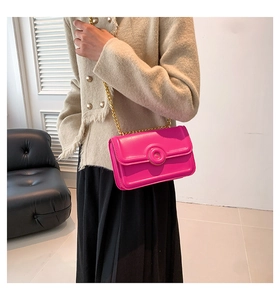 Detail of a bright pink chain shoulder bag with a gold round buckle on tweed fabric