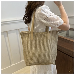 Dettaglio della borsa tote in paglia beige con trama fitta e tracolle in similpelle