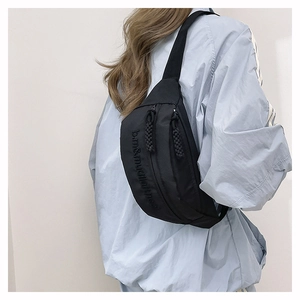 Detail shot of black nylon chest bag with embossed lettering and braided zipper pull