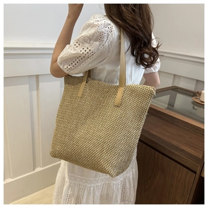 Dettaglio della borsa tote in paglia intrecciata con spalline in pelle marrone per estate