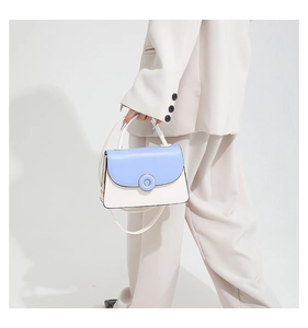 Femme élégante portant un sac bandoulière carré bleu et crème avec un tailleur beige