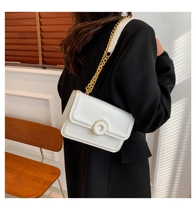 Minimalist white leather shoulder bag with gold chain strap shown on a model