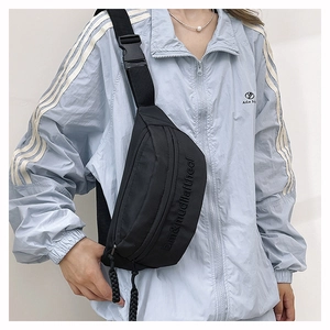 Detail of black nylon chest bag with embossed lettering and adjustable buckle strap