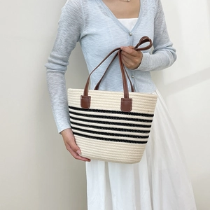 Beige woven straw tote bag with black horizontal stripes and brown leather handles