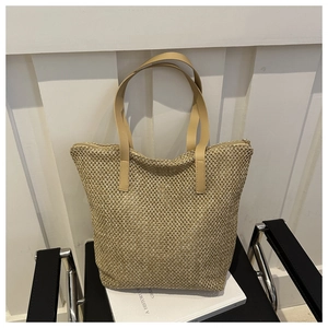 Dettaglio della borsa tote in paglia intrecciata con manici in ecopelle marrone e zip di chiusura