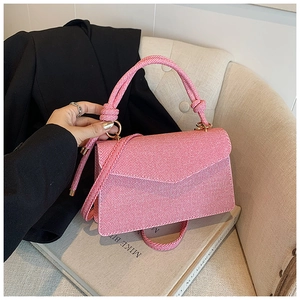 Detail of pink striped crossbody bag with knot rope handle on a lifestyle background