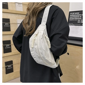 Detail of white crossbody bag featuring stylish 3D letter embroidery and woven zipper pull
